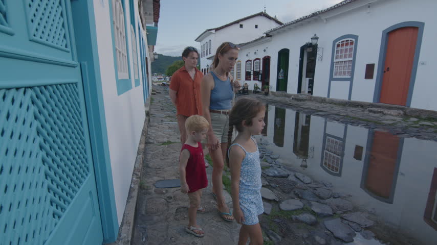 Tourists walk on the street of the colonial town of Paraty filled with water, Brazil