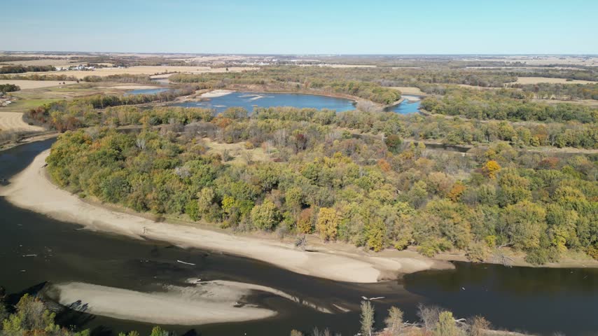 Looking from above at lakes and the river bending with fall trees all around in the countryside of rural Iowa. Flying in a drone, 4k, fall