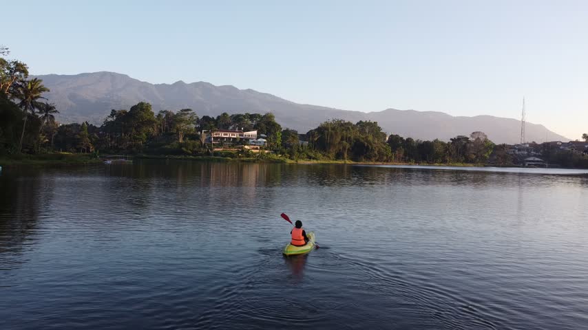 Person Kayaking on a Calm Mountain Lake Surrounded by Scenic Nature