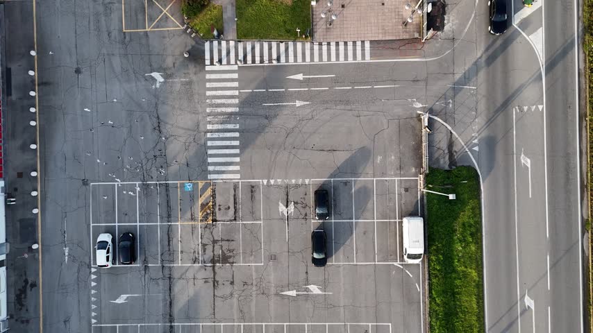 Strada Padana Inferiore crosses Castelvetro Piacentino, Piacenza, Emilia-Romagna, Italy, beside commercial buildings, marked parking and local streets, with the town fabric beyond, drone tilt up.