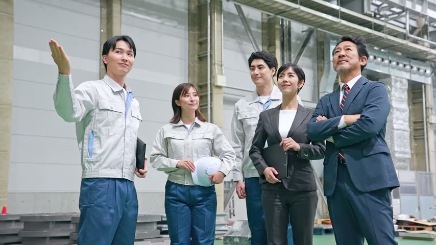 A male worker giving a visitor a tour of the factory.