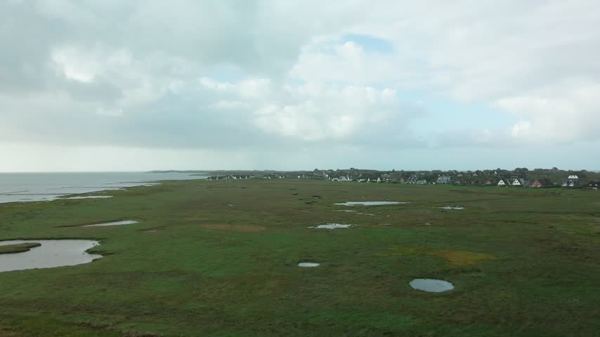 Ascending drone shot at Rantum on Sylt showing tidal creeks and pools in the salt marsh with the Wadden Sea on one side and the North Sea on the other