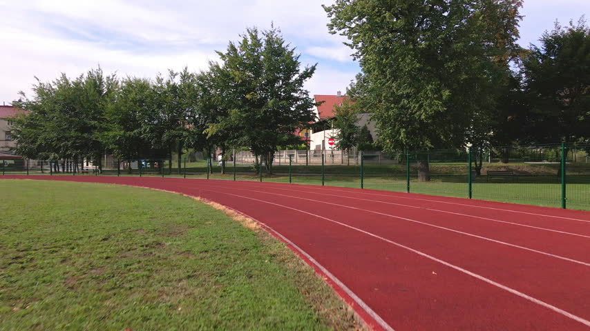 Woman running on a track during outdoor exercise. Female runner training at a sports field. Fitness, sport and active lifestyle.