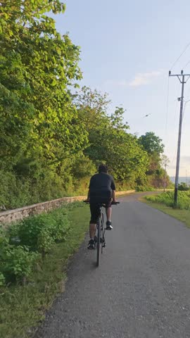 Person Riding a Bicycle on a Country Road