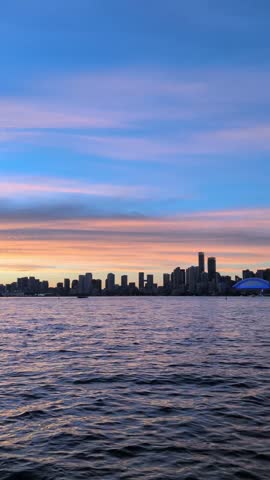 Evening in Toronto with a beautiful blue sky—downtown skyline and a calm lake. View from the island. Vertical video, pan shot. Toronto, Ontario, Canada 