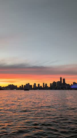 Evening in Toronto with a beautiful blue sky—downtown skyline and a calm lake. View from the island. Vertical video, pan shot. Toronto, Ontario, Canada 