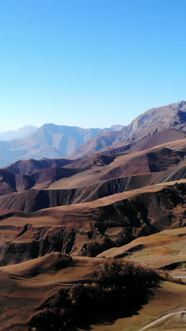 Arid mountain landscape with winding road under clear blue sky