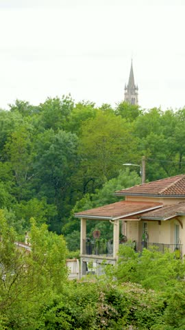 Scenic view of a terracotta roofed house and church spire in Saint-Ãmilion, France.