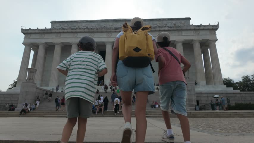 Back view of a mother and her two young boys walking toward the lincoln memorial in washington d.C., a famous historic landmark and tourist attraction celebrating american heritage
