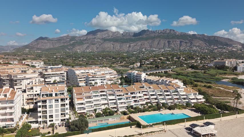 The coastline of Costa Blanca in Albir and Altea, Spain. You can see sunny skies, buildings near the shore, and the Mediterranean Sea.