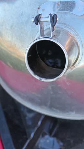 Vertical close-up of water bubbling rapidly from heat inside a metal travel kettle, looking directly into the open spout.