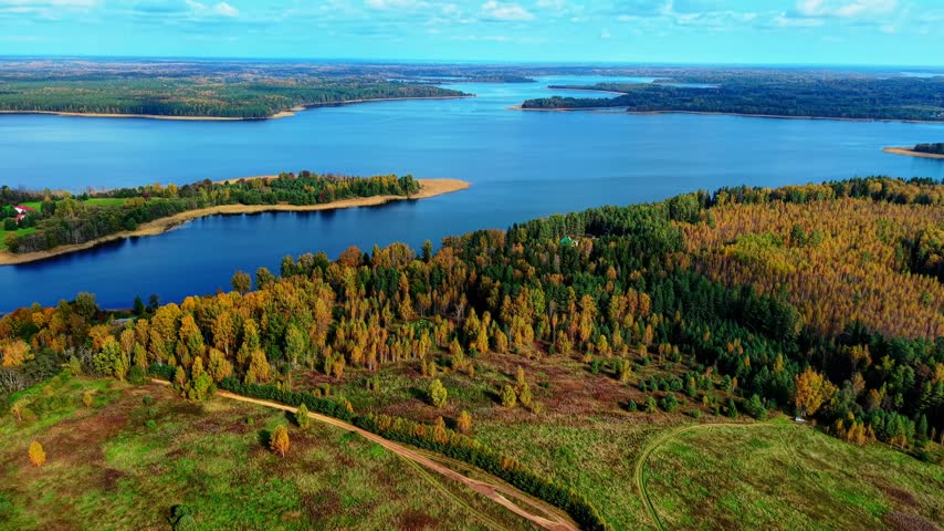 Autumn landscape featuring vibrant trees, expansive lakes, and winding paths under clear skies