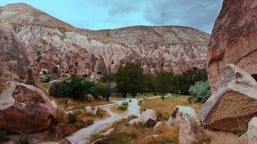 Wide view of rocky valley landscape with walking paths and scattered trees in Turkey
