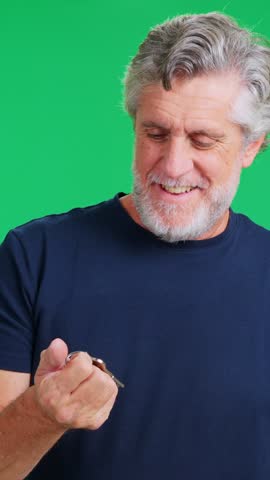 Cheerful older man with a beard showing off his new home keys on a green screen background