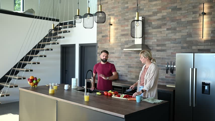 Man and woman talking and cooking a healthy meal in a modern kitchen with an industrial design