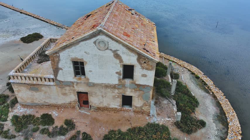 An old, abandoned brick house on an island, viewed from a bird