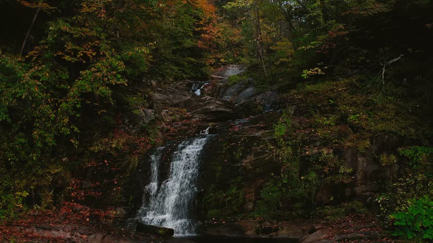 Drone pans backward over Enders Falls river revealing the lush forested landscape of Granby Connecticut