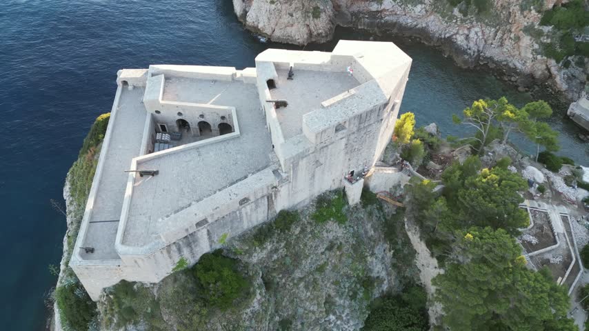 Fort Lovrijenac Standing On A Dramatic Cliff Edge Above The Blue Waters Of The Adriatic Sea In Dubrovnik, Croatia. - aerial shot