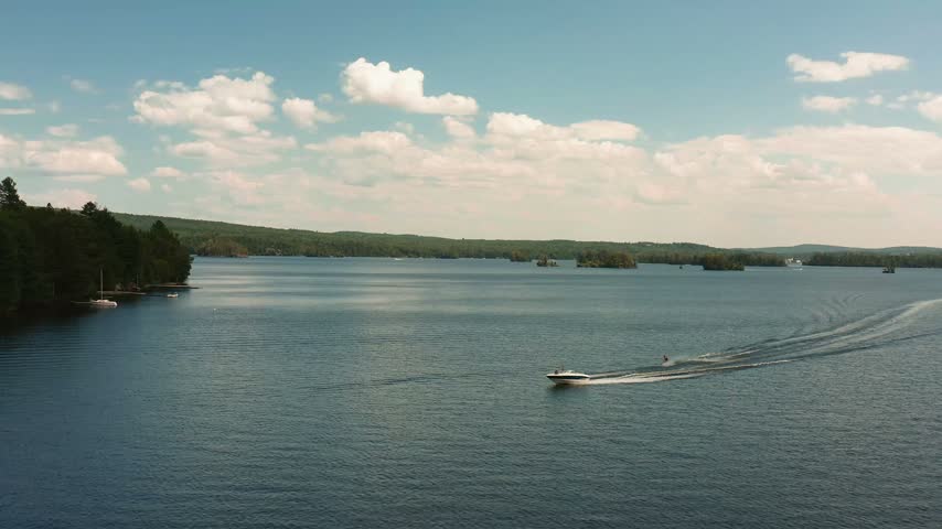 A boat with water skis glides across the surface of Moosehead Lake Maine on a summer day