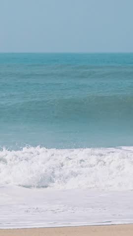 Large ocean wave curling and forming a smooth crest, vertical coastal footage