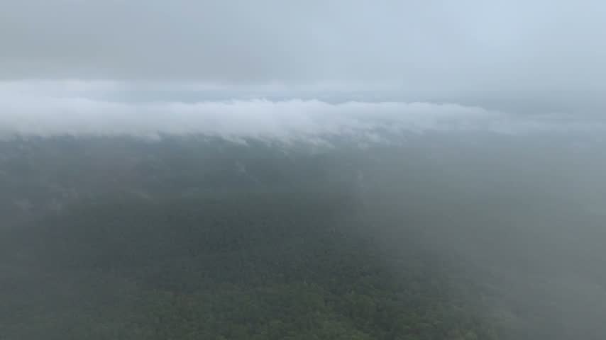 Forward flight through low clouds into a forested mountain valley along the Talimena National Scenic Byway in southeastern Oklahoma.