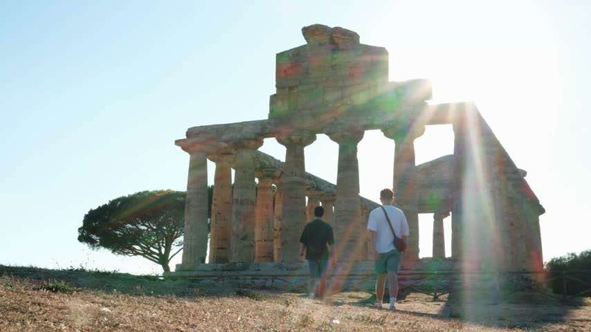 Two men stand in front of the Temple of Athena, Paestum, at sunset