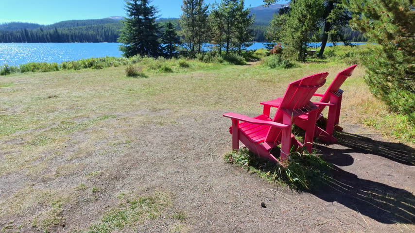 peaceful summer afternoon, with iconic red Adirondack chair overlooking the sparkling blue waters of Maligne Lake in Alberta of Canada in Jasper National Park