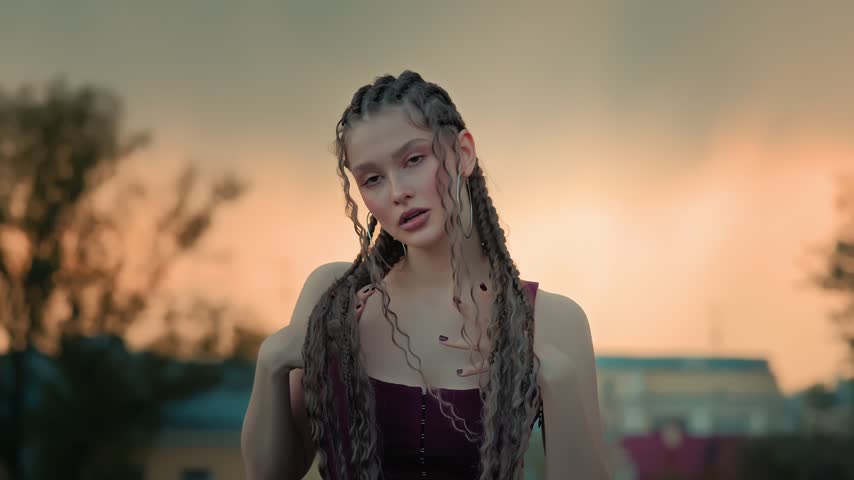 Young Woman Raising Arm in Sunset Portrait With Braided Hair, Calm Expression and Warm Outdoor Light