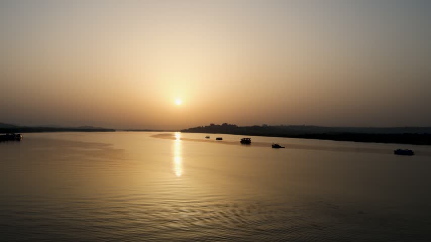 Peaceful River Landscape At Sunset With Boats And Distant Shoreline