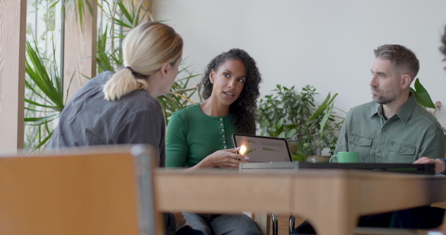 Colleagues Engaged in Discussion at Table using Digital tablet