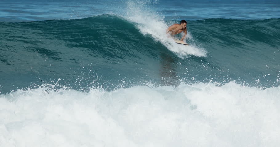 Surfer man rides on surfboard on ocean wave. Summer surfing, slow motion