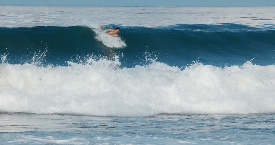 Surfer man rides on surfboard on ocean wave. Summer surfing, slow motion