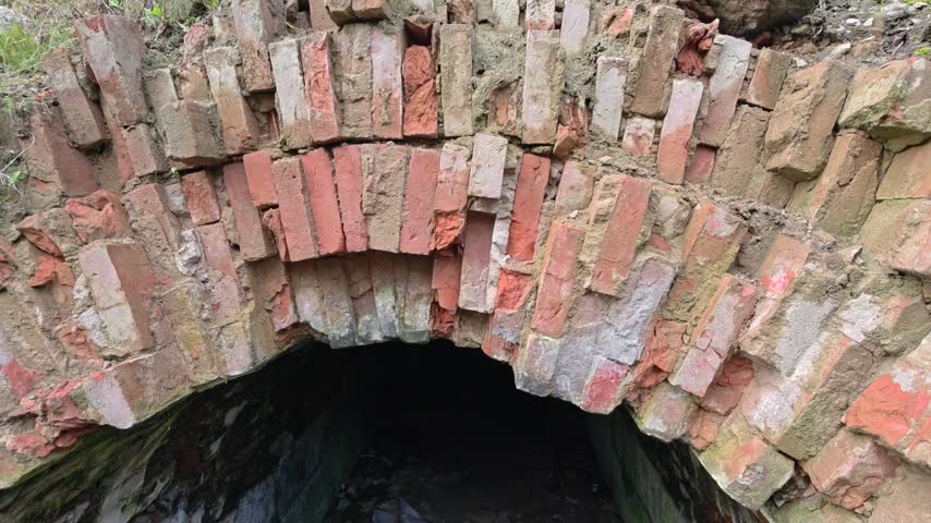 brick tunnel in the woods, great for outdoor, nature, or wildlife scenes.