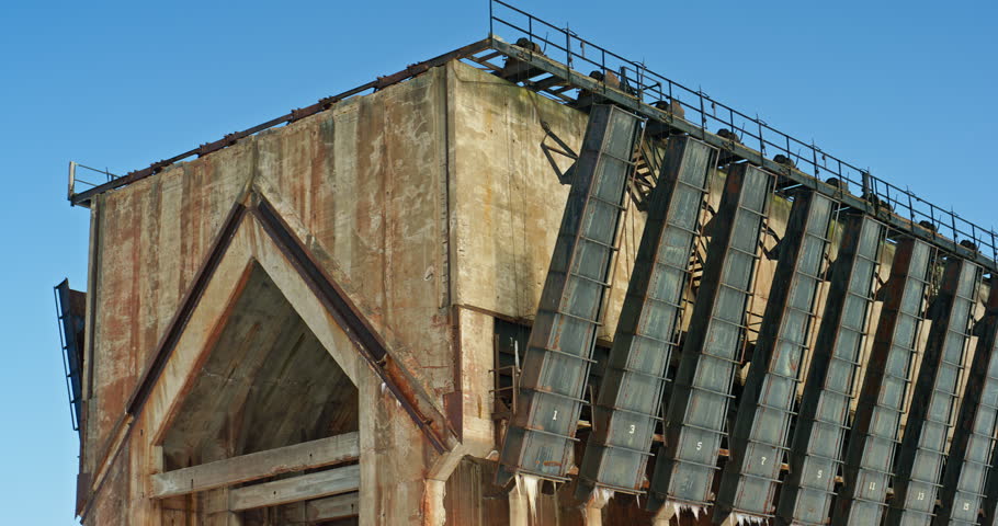 Close moving view pans across the weathered steel loading chutes and concrete end structure of Marquette