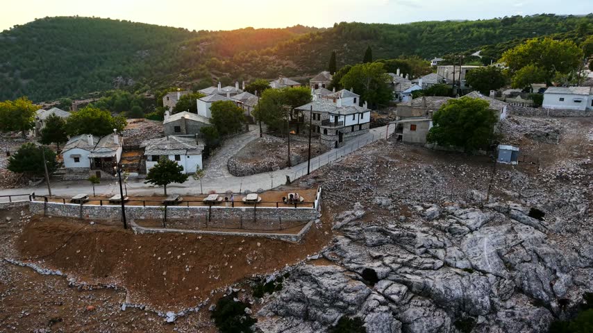 Drone pulls back over the traditional stone mountain village of Kastro into the mountains of Thassos, Greece, at sunset