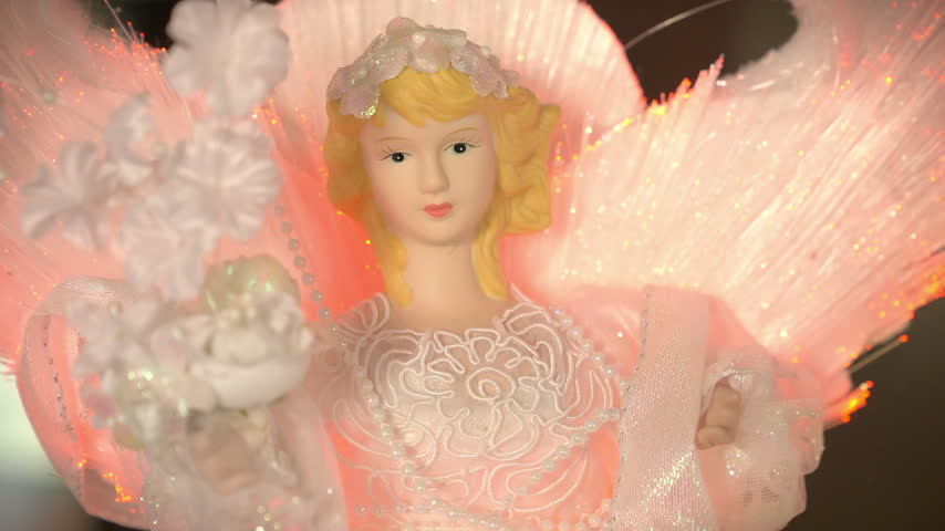 An electric, old-fashioned angel with blonde hair ornament with glowing lit-up wings. 