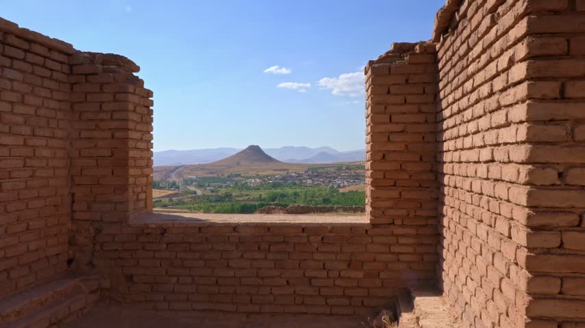 View of the Prison of Solomon a hollow cone-shaped hill seen through a rectangular opening in the brick enclosure of Takhte Soleyman (Throne of Solomon) an archaeological site in West Azerbaijan, Iran. The site holds the ruins of the most significant Zoroastrian fire temple from the Sassanid period