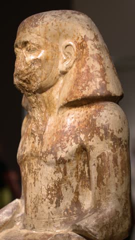 Close-up panning shot of an ancient Egyptian limestone statue at Egyptian Museum in Turin, Italy.