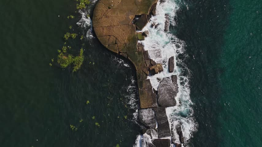 Aerial view of rocky breakwater with crashing waves along the coastline in Santo Domingo, Distrito Nacional, Dominican Republic.