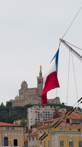 The French national flag flutters before Notre Dame de la Garde basilica overlooking Marseille.