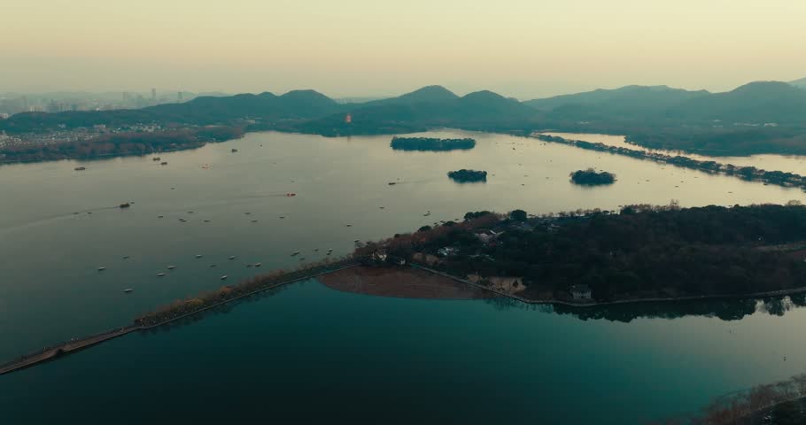 Aerial view of tranquil lake with islands and distant mountains at dusk