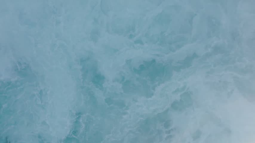 Aerial View of Turquoise Waterfall Churning Over Snow-Covered Rocks