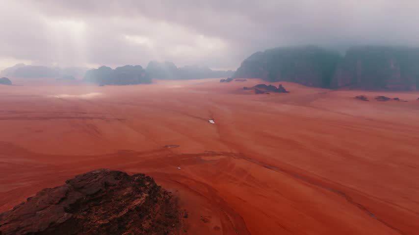 Vast red desert landscape under cloudy sky with rocky formations