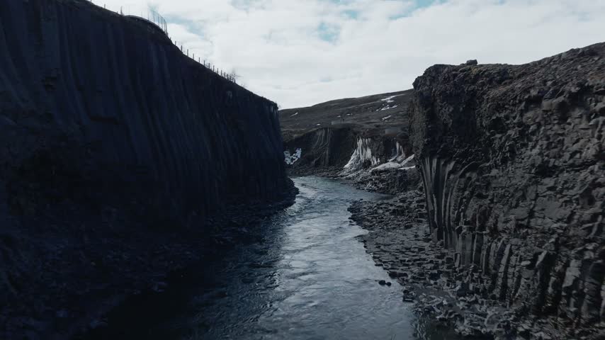 A glacial river flows through narrow rocky canyon with ice formations
