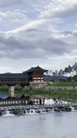 Traditional Korean palace bridge reflected in a pond with flowing water