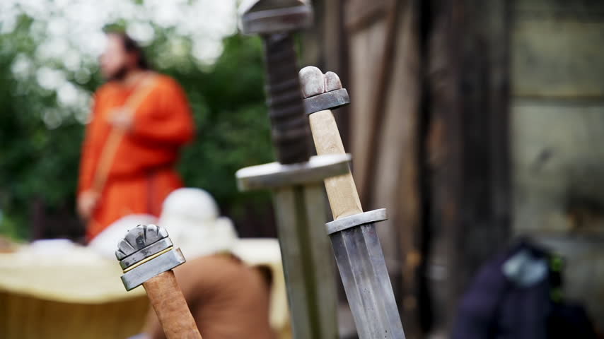 Three Viking swords stuck in wooden log after intense battle outdoors.