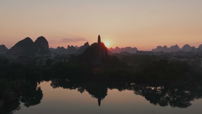 Aerial view of a pagoda on a hill reflecting in the water during sunset in Guilin, Guangxi, China.