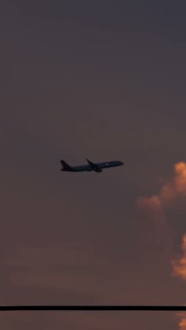Airplane flying above clouds during a beautiful sunset, centered in the frame with warm golden light and a colorful evening sky.