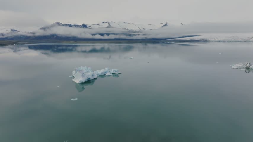 Serene Arctic Lake Reflecting Snow-Capped Mountains and Icebergs