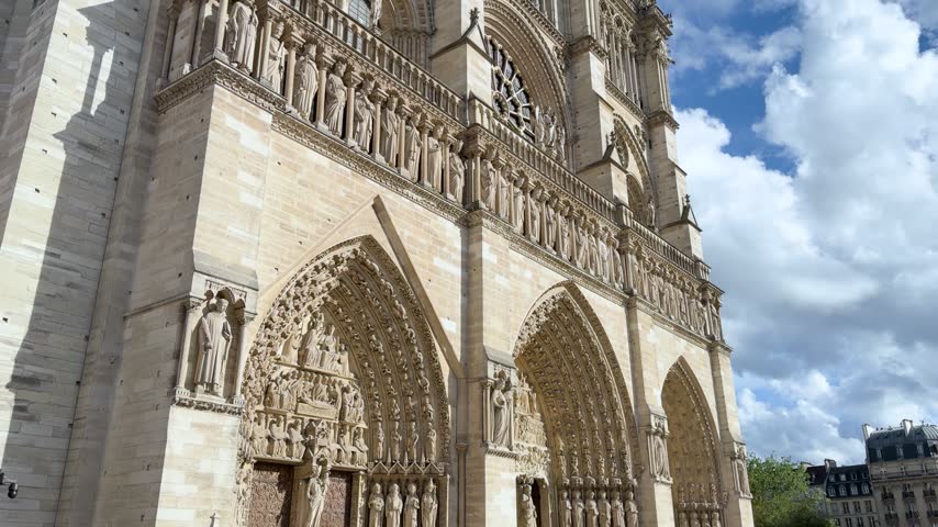 Low angle tilt up shot of the historic Notre Dame Cathedral facade in Paris, France.